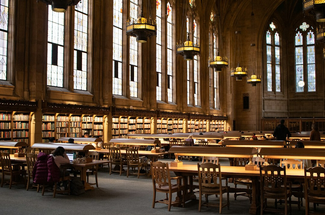 Historic library interior with tall wooden bookshelves and reading tables